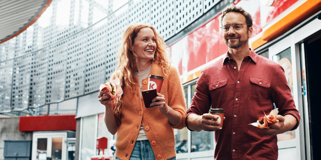 A woman and a man at Circle K carrying coffee and snacks