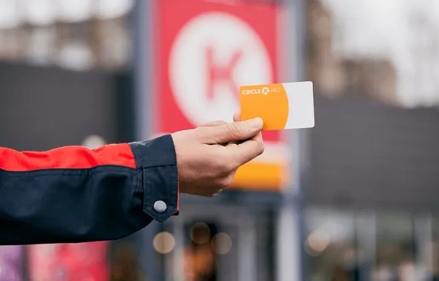 person holding a fuel card outside a Circle K 