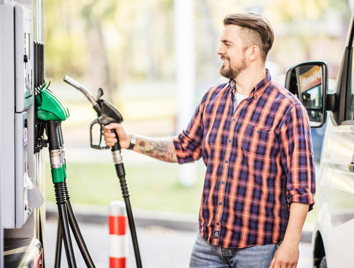 A man holding a fuel nozzle next to a petrol pump